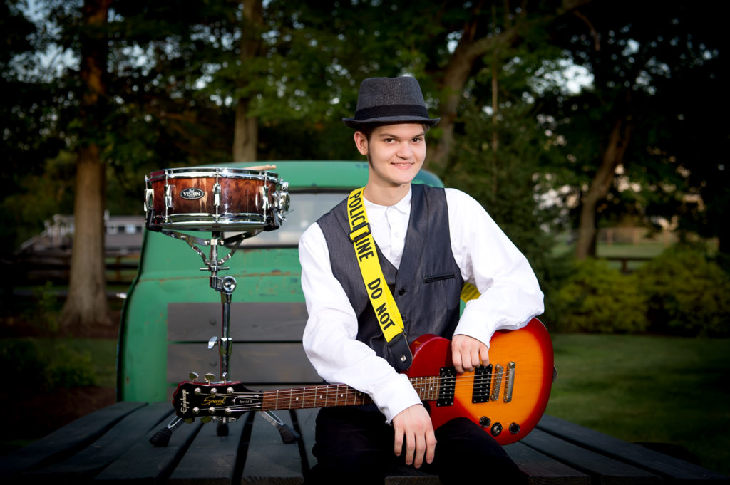 senior boy with drums and guitar outdoors